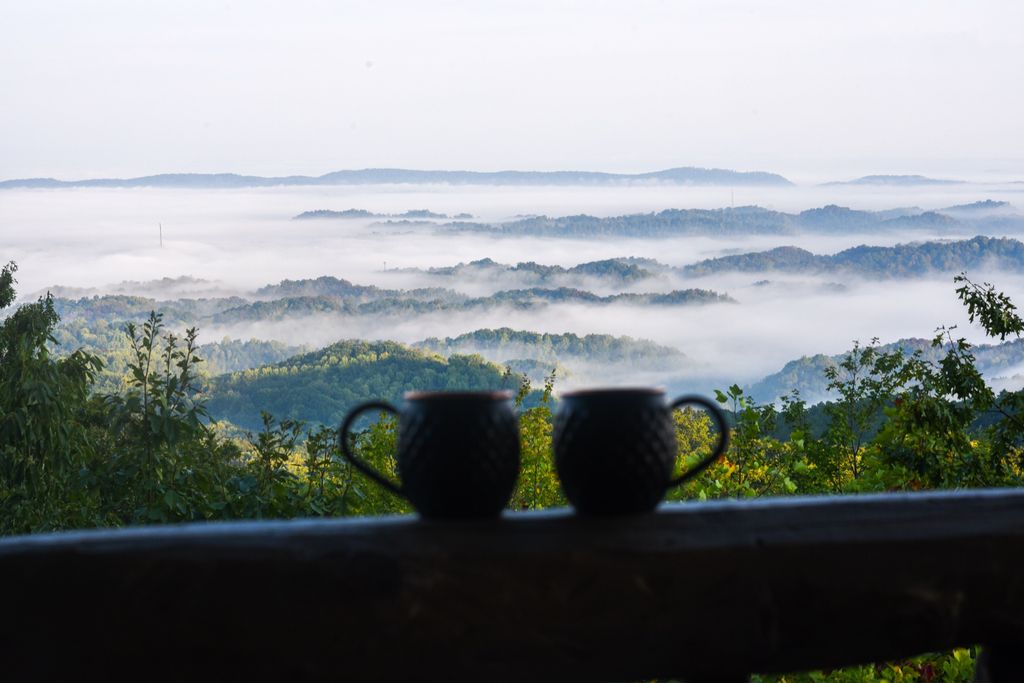 Two mugs on the rail above the morning fog