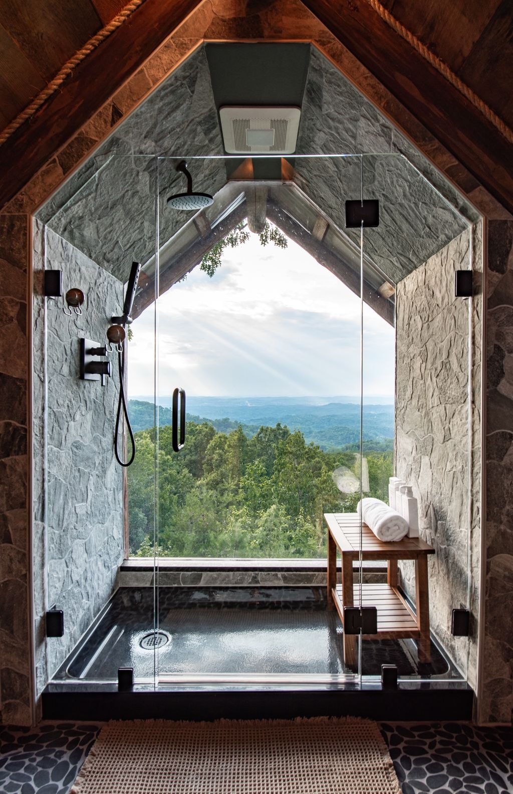 Walk-in stone shower with a floor-to-ceiling mountain view window