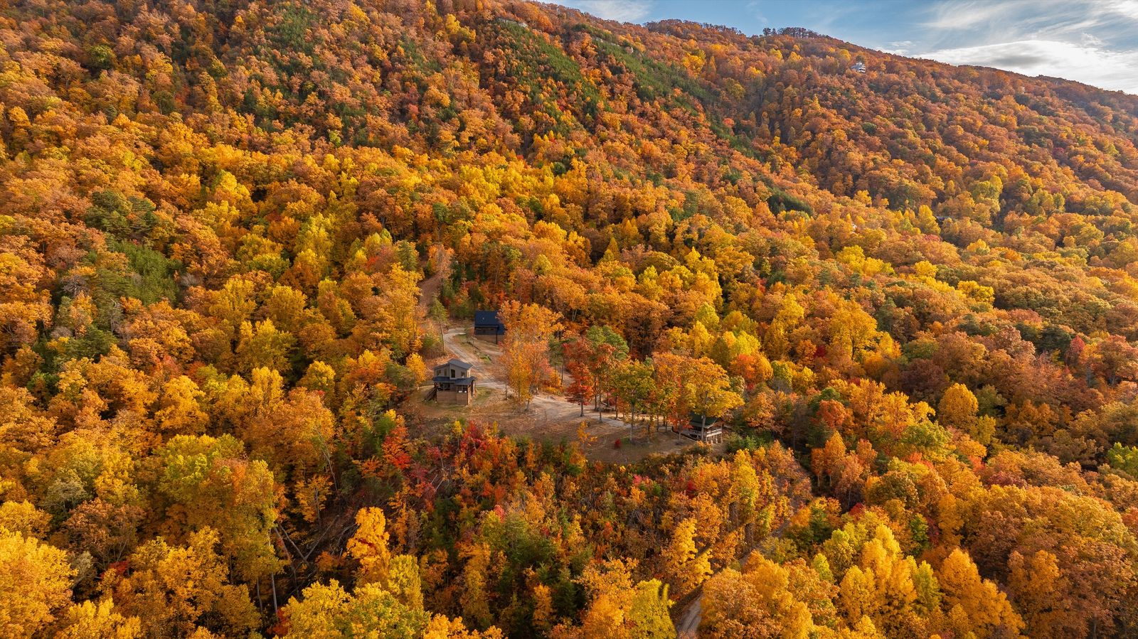 Aerial view of all three cabins on the ridge surrounded by peak fall color
