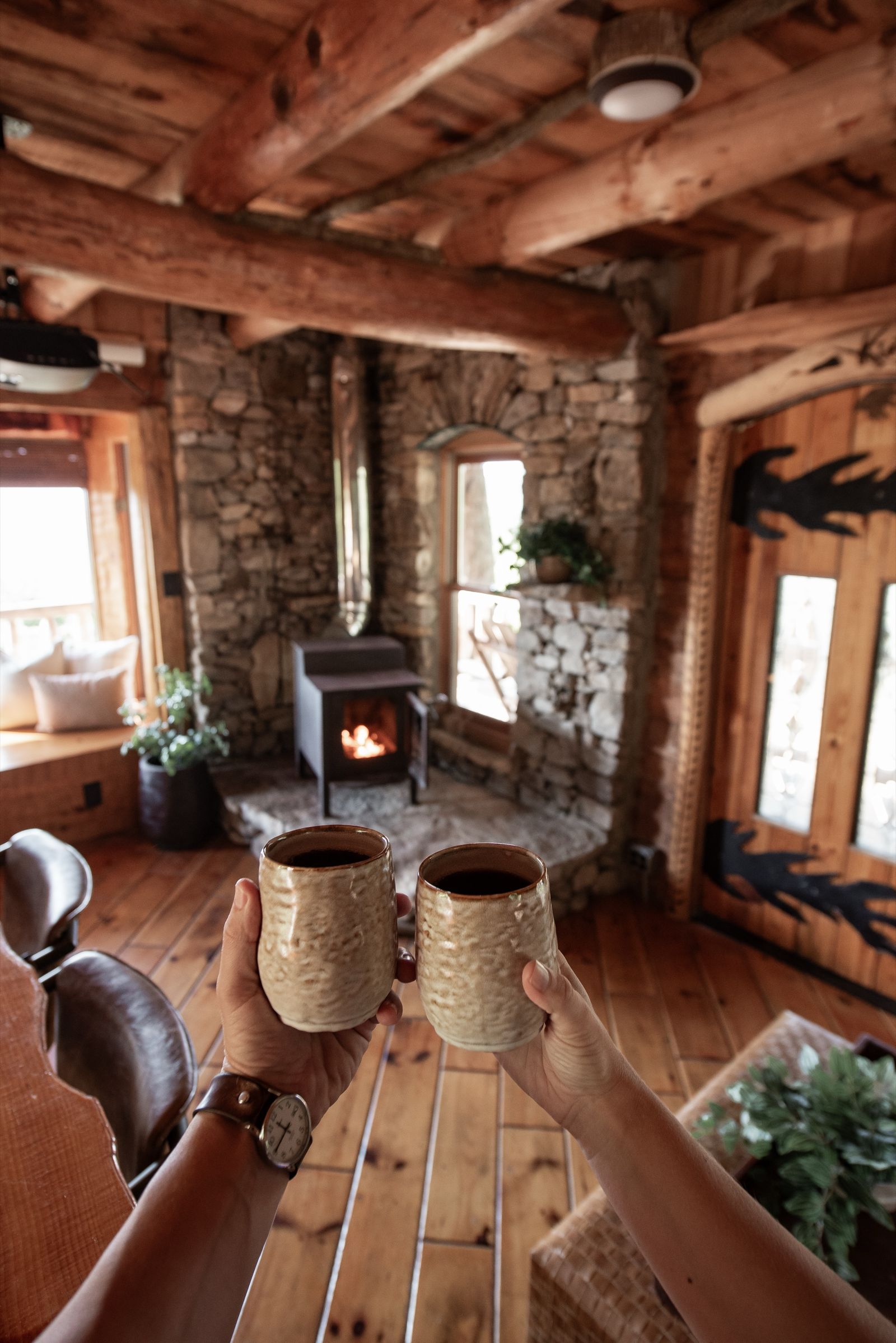Guests toasting coffee mugs by the stone fireplace